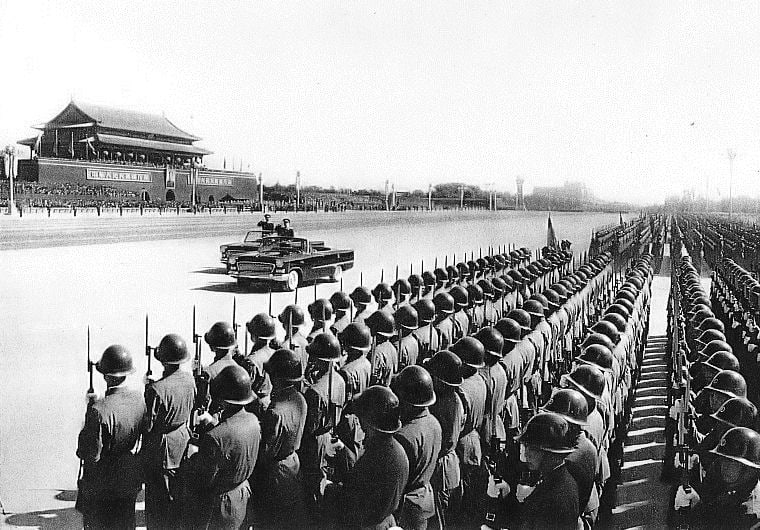 Ein offener Paradewagen fährt bei der Parade zum 10. Jahrestag der Volksrepublik 1959 in Peking an Reihen von Soldaten vor dem Tian’anmen vorbei