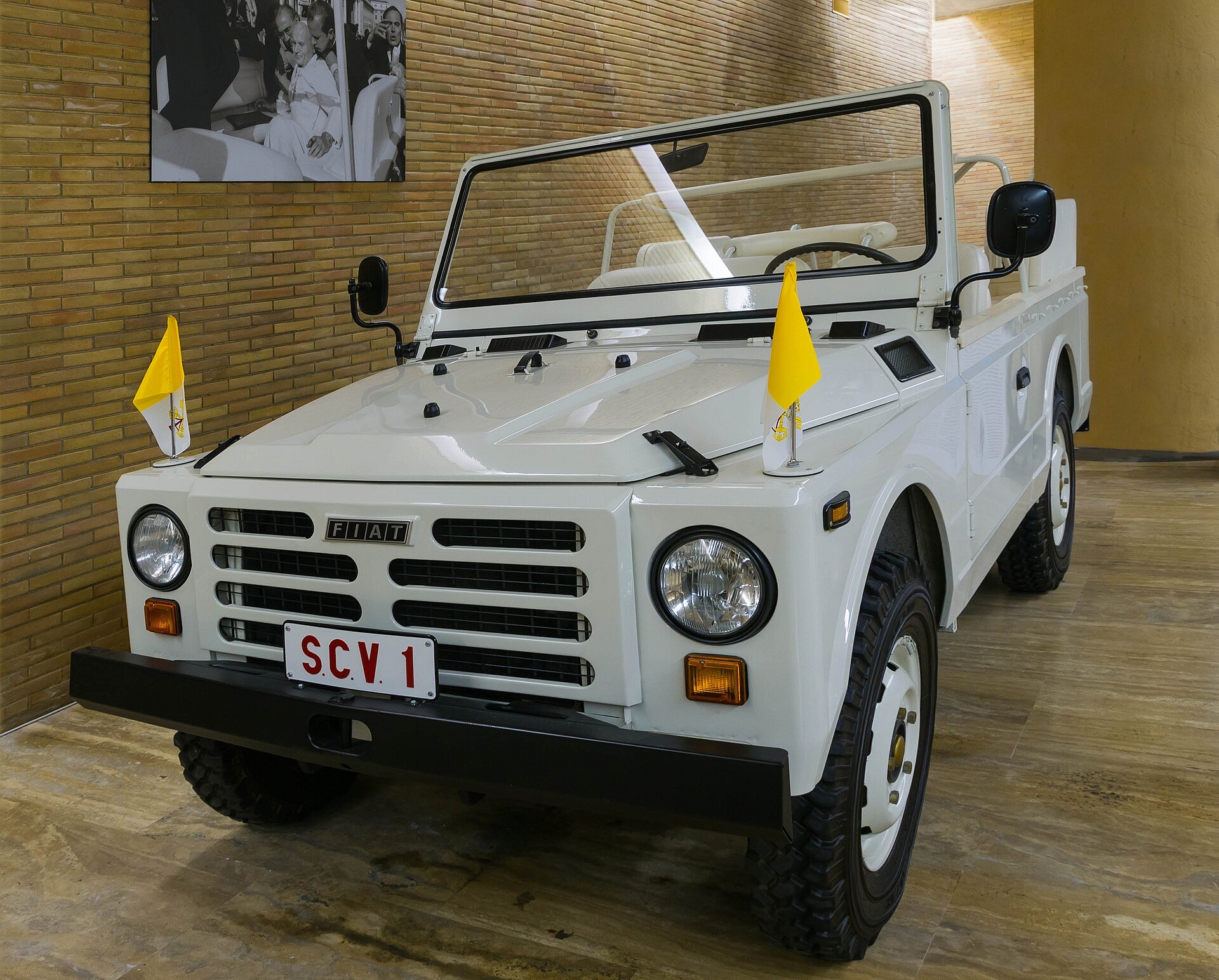 Der offene weiße Fiat Campagnola, in dem Papst Johannes Paul II. am 13. Mai 1981 angeschossen wurde, mit gelb-weißen Fahnen und dem Kennzeichen SCV 1, ausgestellt