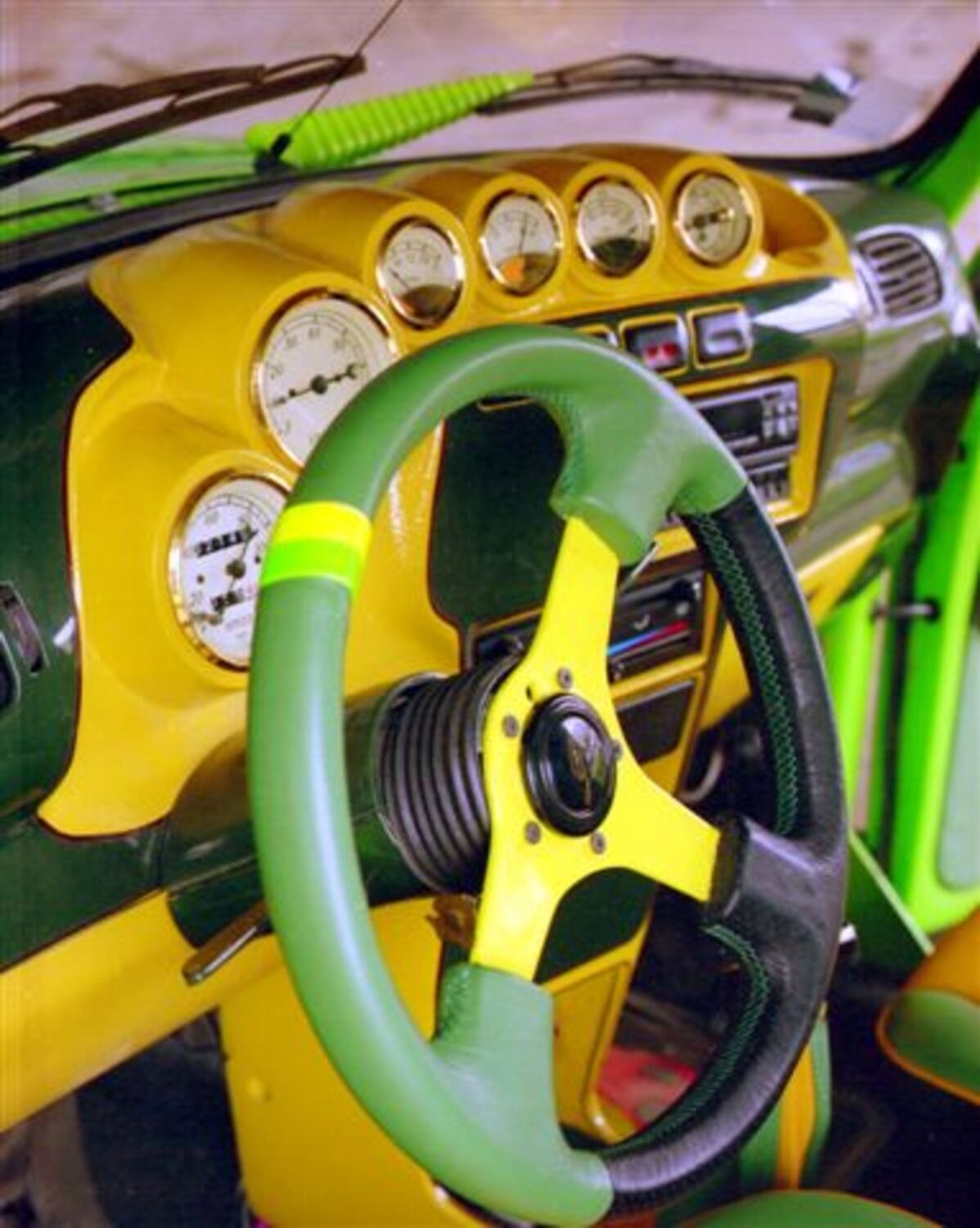 Inside the DARTZ VW Froggy: a green and yellow cabin with a three-spoke wheel and a row of chrome gauges